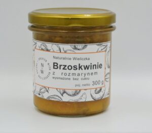 Słoiczek ze złotą zakrętką z etykietą z napisem Brzoskwinie z rozmarynem